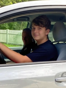 A Saint Basil Academy young man in the driver's seat of a car