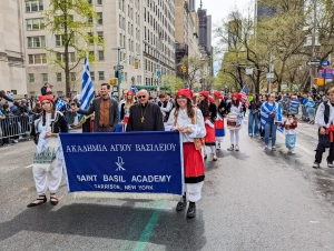 two young ladies holding a Saint Basil Academy sign while walking with others in the Greek parade in New York City