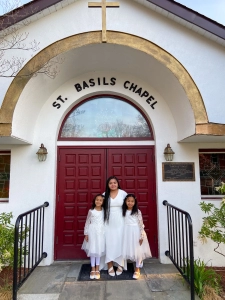 A lady with her arms around two girls standing on either side of her in front of Saint Basils Chapel