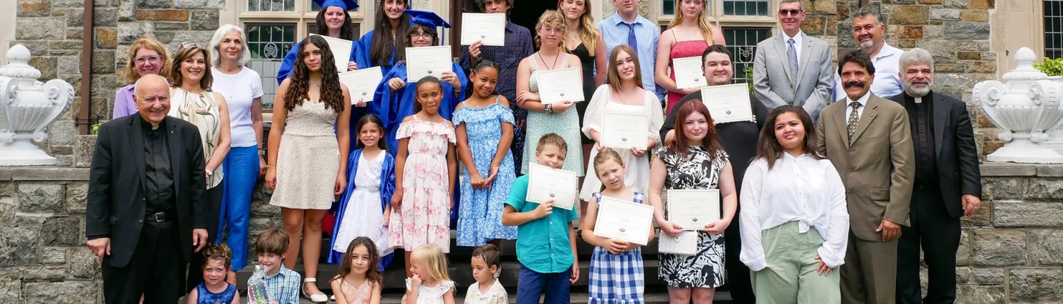 Graduation students with adults in front of the Saint Basil Academy main building