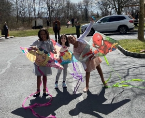 Three girls posing with their kites outdoors