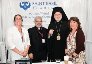 Archbishop Elpidophoros standing with a priest and two ladies