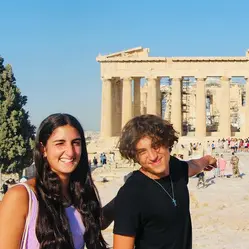 Two students from the Ionian Village in front of archeological ruins with large columns