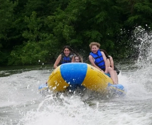 Students on a raft with waves splashing