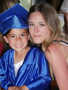 A lady next to a young girl in a blue graduation cap and gown