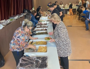 People in front of a line of tables being served food during a panygiri-style Easter Picnic put on by the PanGregorian Enterprises of New Jersey