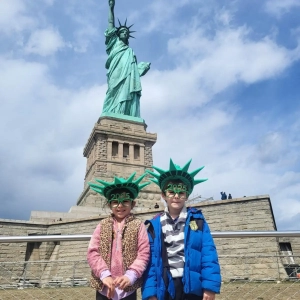 A girl and a boy standing at the base of the Statue of Liberty