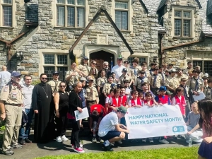 A group of adults and children in front of Saint Basil Academy with a sign that says, 