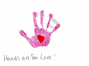 A pink hand print with a red heart painted in the palm on a white background. Written underneath is, "Hands are for Love!"