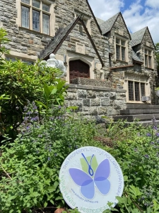 The front of the Saint Basil Academy building with a Pollinator Pathway sign in the greenery