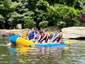 Saint Basil Academy youth sitting on an inflatable raft in the water at Rocking Horse Ranch