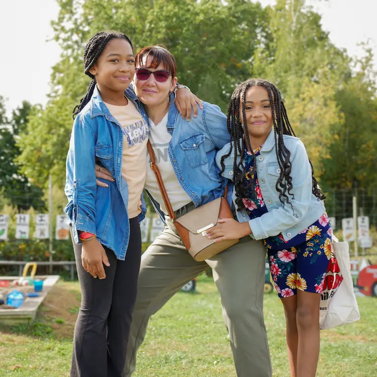A lady between two girls with her arms around both