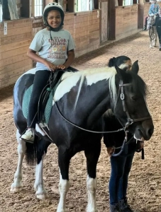 A girl smiling while riding on a horse in an arena