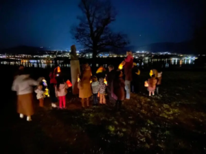 Adults and children carrying lights at night during the annual lantern walk across the Saint Basil campus