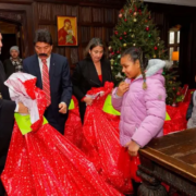 Archbishop Elpidophoros and other adults holding large bags of gifts for the children and youth of Saint Basil Academy