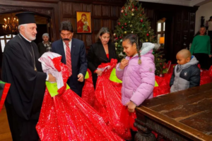 Archbishop Elpidophoros and other adults holding large bags of gifts for the children and youth of Saint Basil Academy
