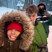 Three youth outside in coats with snow falling