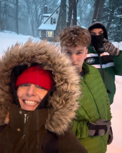 Three youth outside in coats with snow falling