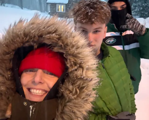 Three youth outside in coats with snow falling