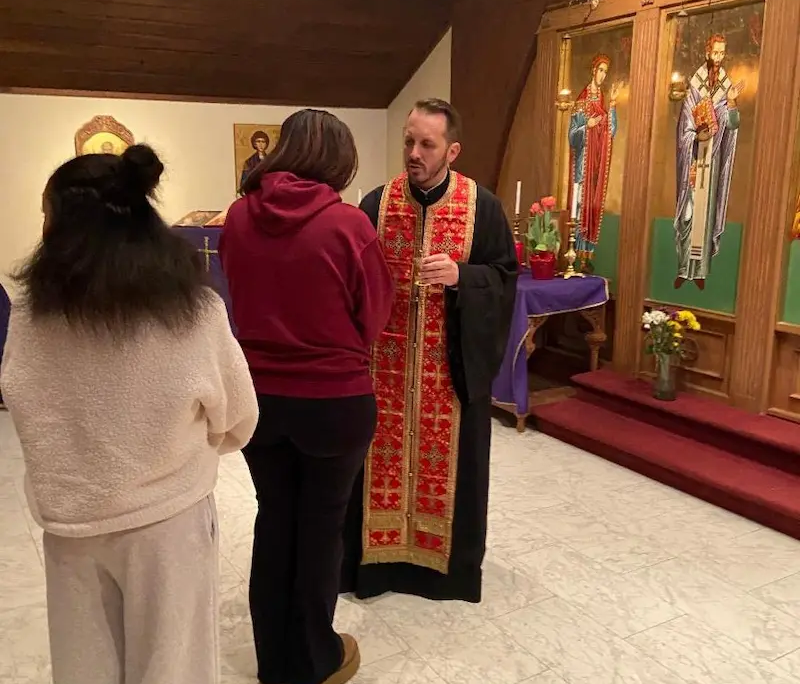 Father Nikolas Belaveris ministering to a youth during a parklesis service at Saint Basil Chapel