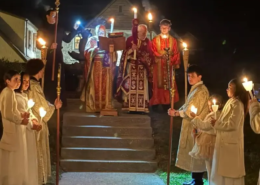 Two priests with the gospel and alter servers holding candles outside in the dark during the Holy Pascha service 2026
