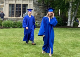 High school graduates Two high school graduates in cap and gown walking across the lawn at Saint Basil Academy