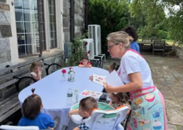 Restaurant day at the playroom A lady holding a menu standing at a table with children seated around it on restaurant day at the playroom.