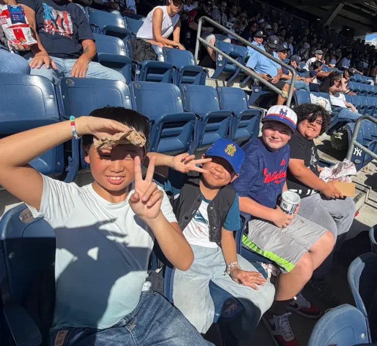 Yankees baseball game Four smiling boys sitting in the stands at a Yankees baseball game