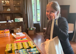 Making back-to-school kits A girl putting school supplies in a white canvas tote bag