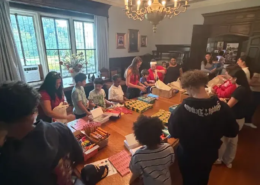 Making back-to-school kits Adults and children standing around a table with school supplies on it as they put them in bags